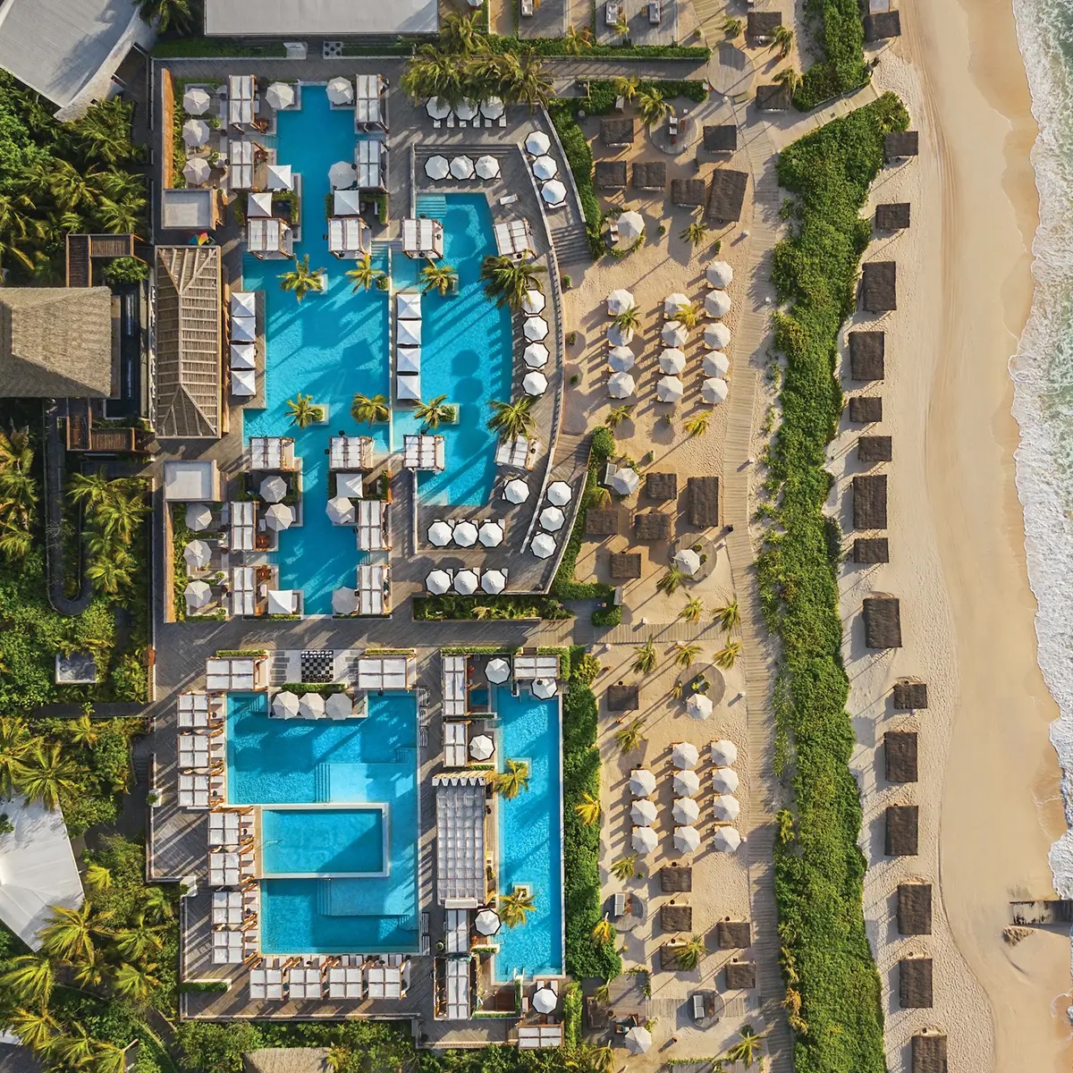 Aerial view of the pool complex and beach area at Vidanta Riviera Maya with loungers and palapas