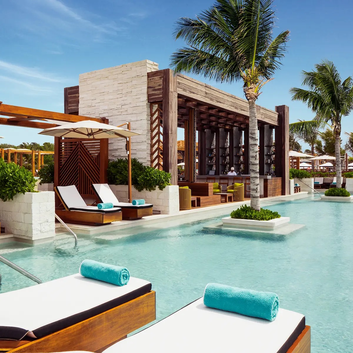 Pool with a swim-up bar and poolside loungers at Vidanta Riviera Maya